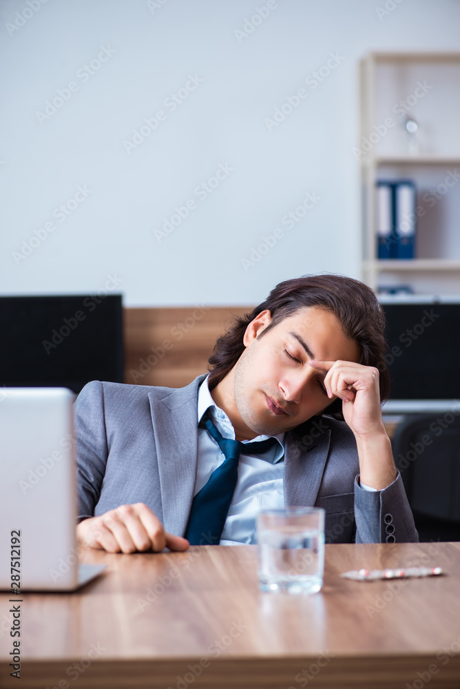 Sick male employee suffering in the office Sick male employee suffering in the office