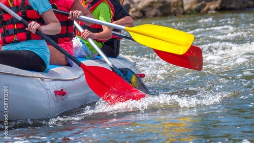 Rafting trip. Close up view of oars with splashes of water. Rowers make an effort to overcome the turbulent river. The concept of teamwork, healthy lifestyle.