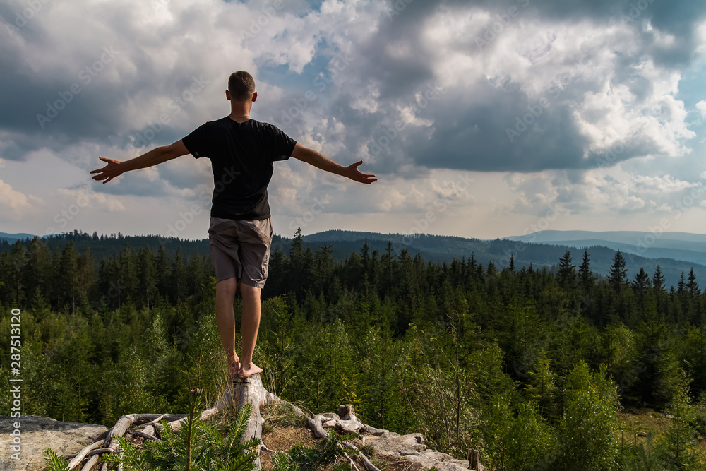 Young man meditating, stretching shoeless on tree stump, Sumava national park, Czech republic Young man meditating, stretching shoeless on tree stump, Sumava national park, Czech republic