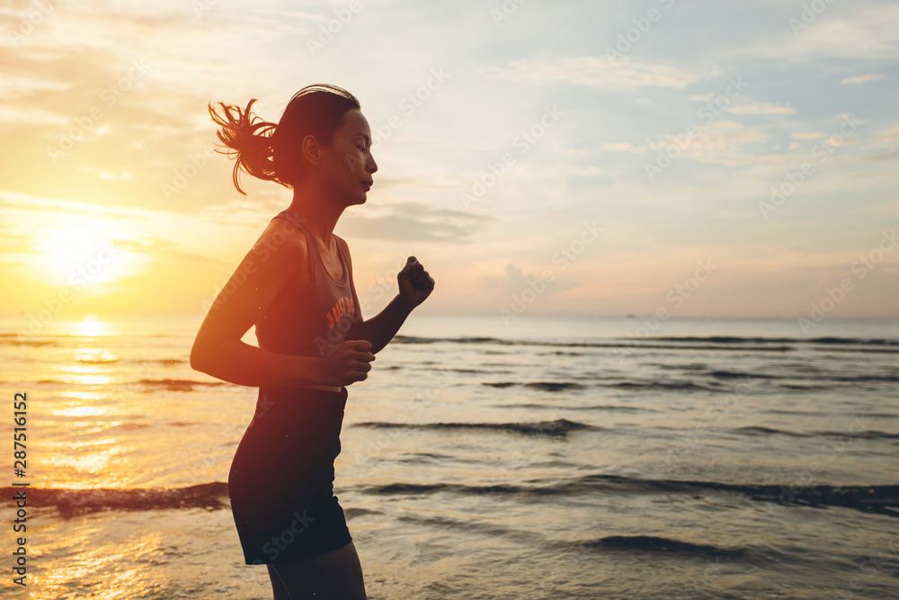 Silhouette of an athletic woman running on the beach during sunset time