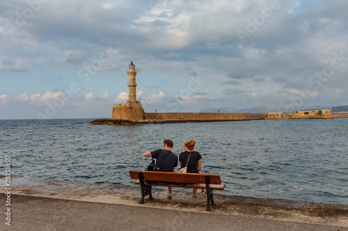 young couple resting on a bench on the promenade of the Greek town of Chania © westermak15