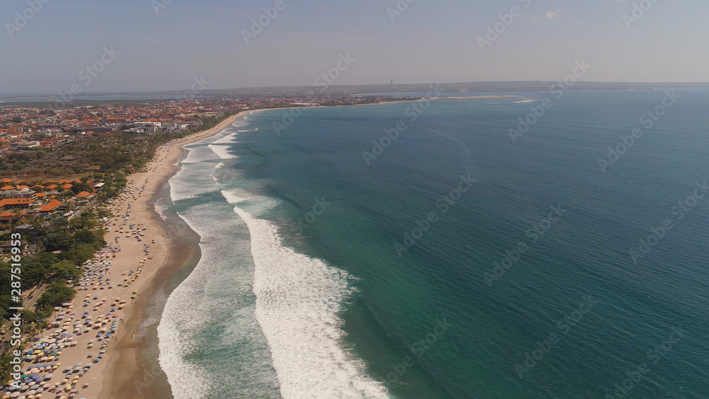 Aerial view sand beach with resting people, hotels and tourists, sun umbrellas, Bali, Kuta. surfers on water surface. Seascape, beach, ocean, sky sea Travel concept