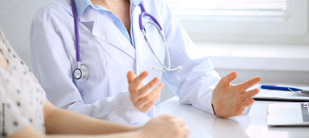Doctor and patient discussing something while sitting at the desk at hospital, close-up. Medicine and health care Doctor and patient discussing something while sitting at the desk at hospital, close-up. Medicine and health care