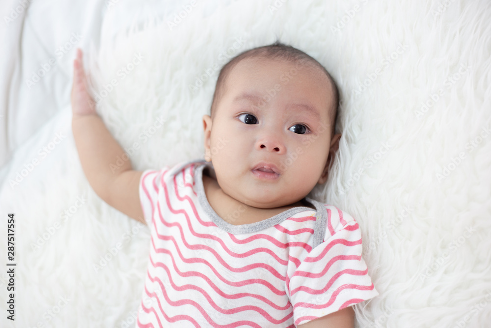 The baby wears a red shirt on the bed. The baby wears a red shirt on the bed.