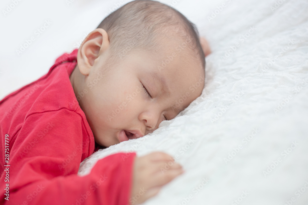 Babies wearing red shirts sleeping in bed Babies wearing red shirts sleeping in bed