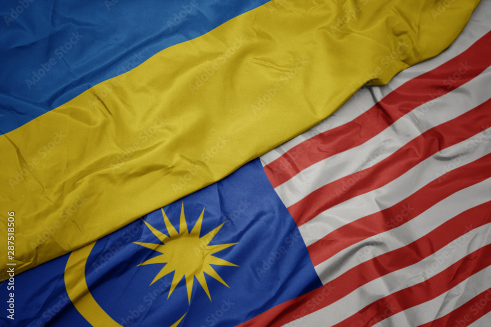waving colorful flag of malaysia and national flag of ukraine.