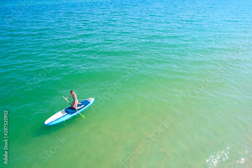 Young woman paddling on SUP board on the tropical beach. Active summer vacations with paddle board. © sarymsakov.com