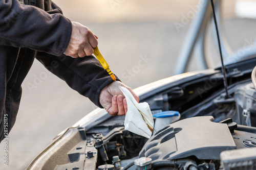 Man is checking oil level on car