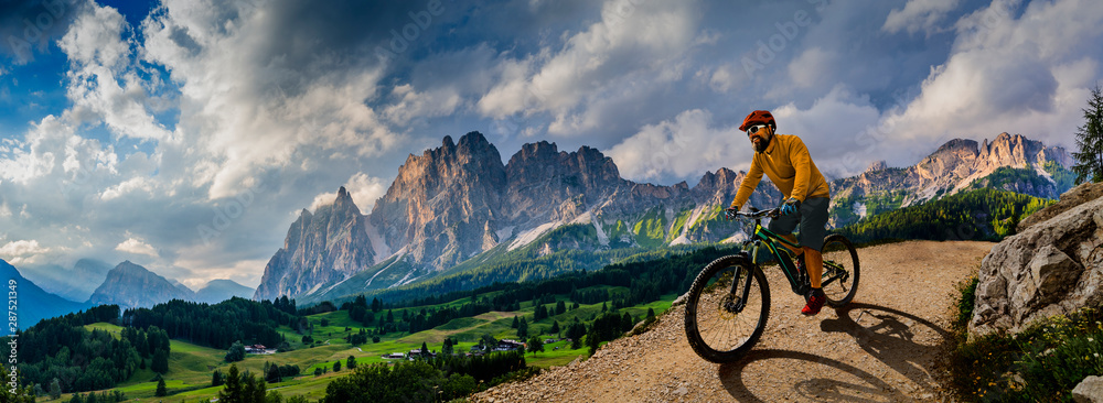 Plakat Mężczyzna na rowerze na rowerze elektrycznym, jeździ górskim szlakiem. Obsługuje jazdę na rowerze w dolomit gór krajobrazie. Trasa rowerowa enduro e-mtb. Aktywność na świeżym powietrzu.