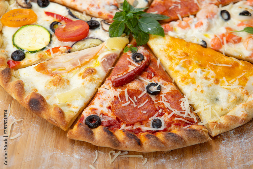 Assorted pieces of pizza closeup with different ingredients decorated with Basil Assorted pieces of pizza closeup with different ingredients decorated with Basil
