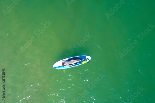 Summer Vacations. Beautiful Young Woman Relaxing on the SUP at Turquoise Water. Beauty, Wellness. Recreation.