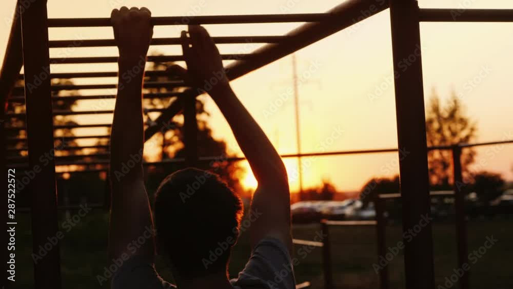 A teenager is training on the stairs, fingering the crossbars. Street training and sports among youth
