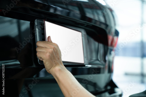 Asian man installing the licence plate of a car. Technician installing car plate. A car plate being install by Asian man. Car license plate black. licence holder adjusting on black vehicle.