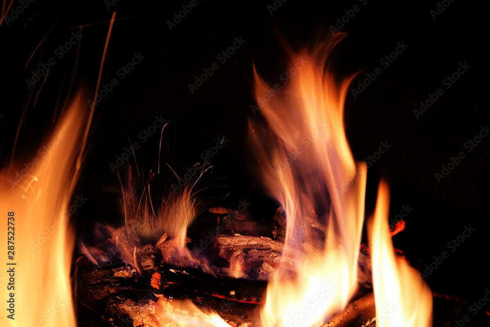 Fototapeta premium Fire, flame on a black background, burning coals and sparks from the fire, motion blur. Abstract background.