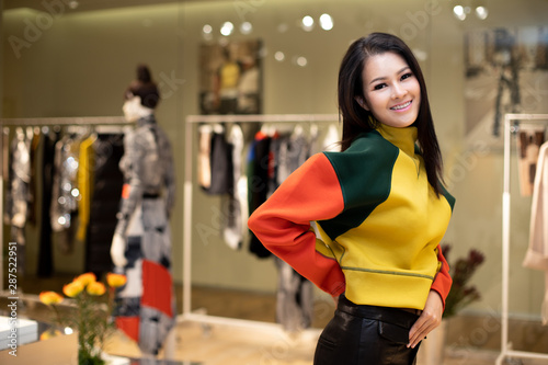 Asian Beautiful Woman in black white dress select new collection on ready to wear clothes rack in retail fashion store which just open brand news for winter autumn as casual style