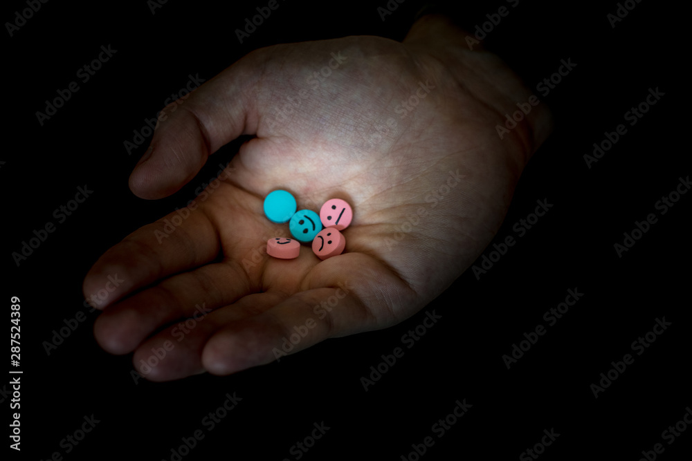 A man holding a multi-colored tablets.  On tablets drawn emoticons.