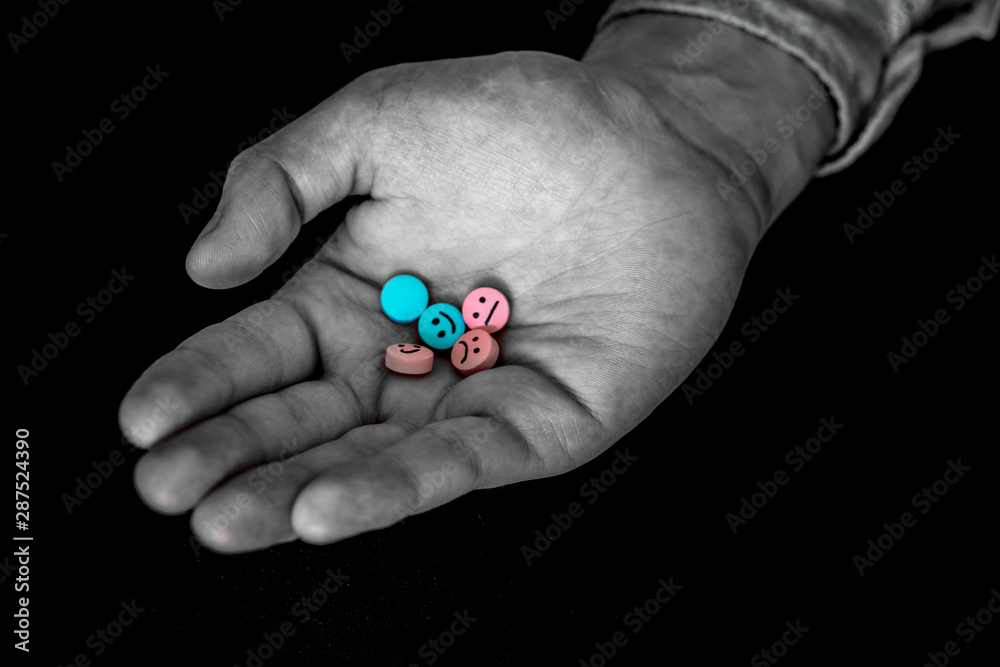 A man holding a multi-colored tablets. On tablets drawn emoticons. A man holding a multi-colored tablets. On tablets drawn emoticons.