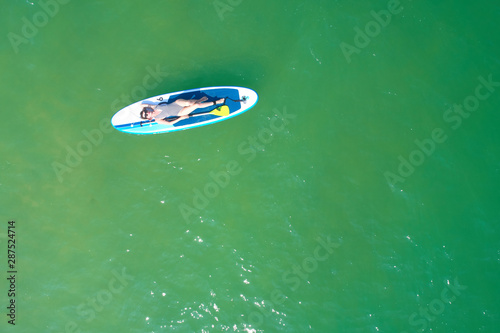 Summer Vacations. Beautiful Young Woman Relaxing on the SUP at Turquoise Water. Beauty, Wellness. Recreation.