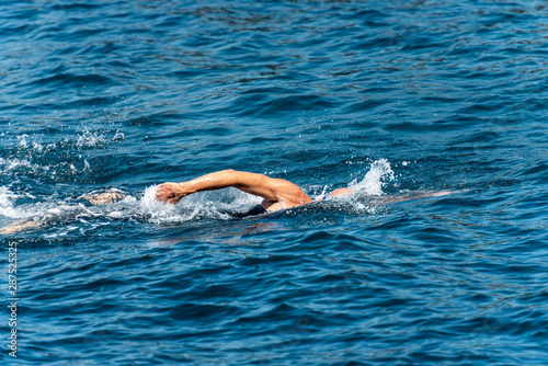 Male freestyle swimmer  Front crawl  in the blue waves of the Mediterranean sea