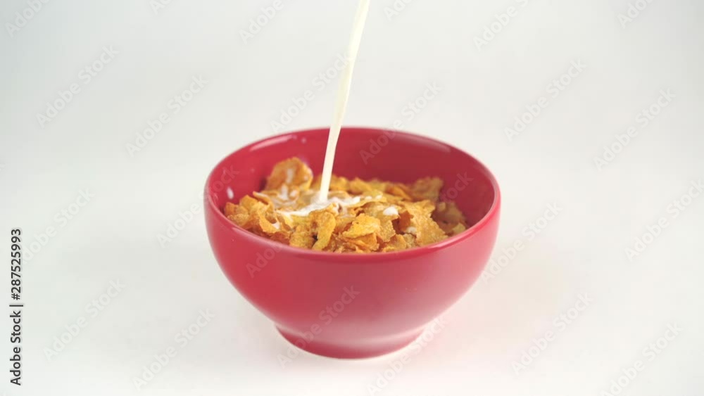 Milk pouring into cornflakes cereal bowl in slow motion Milk pouring into cornflakes cereal bowl in slow motion