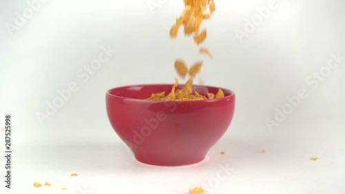 Slow motion cornflakes being poured into cereal bowl photo