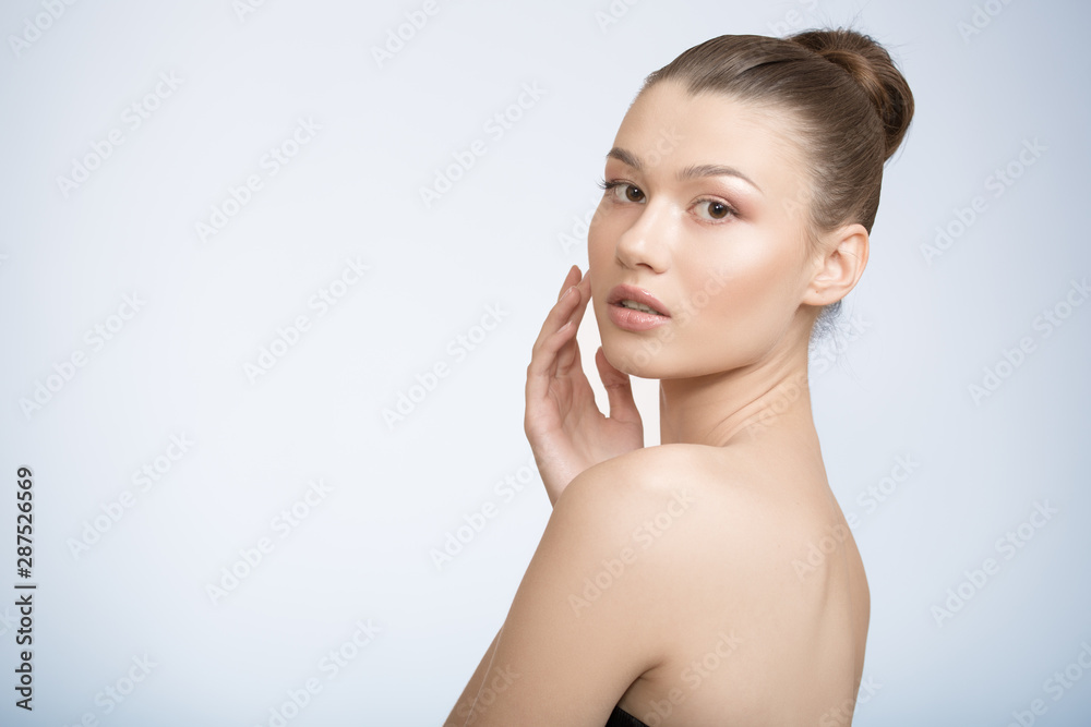 woman with clean skin touches her cheek with her hand. Perfect face skin concept on a blue background.
