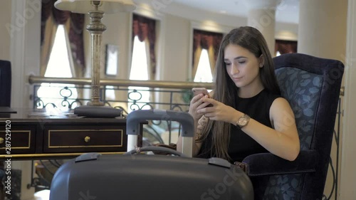 Young girl reading phone messages in hotel untill waiting her room