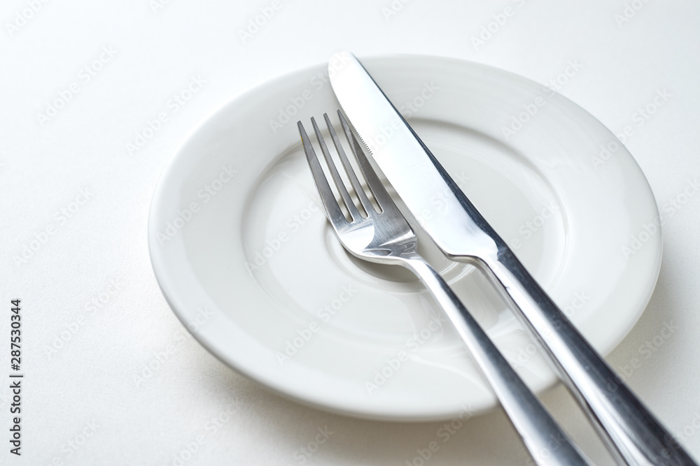 Fork and knife on a white plate on a white background Fork and knife on a white plate on a white background