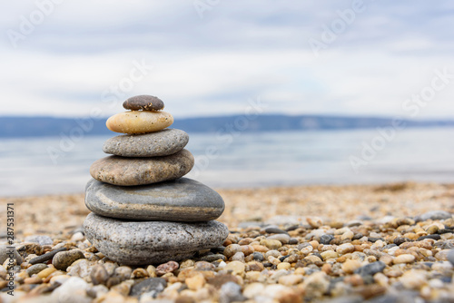 Stones balances on the beach of blue sea with mountain