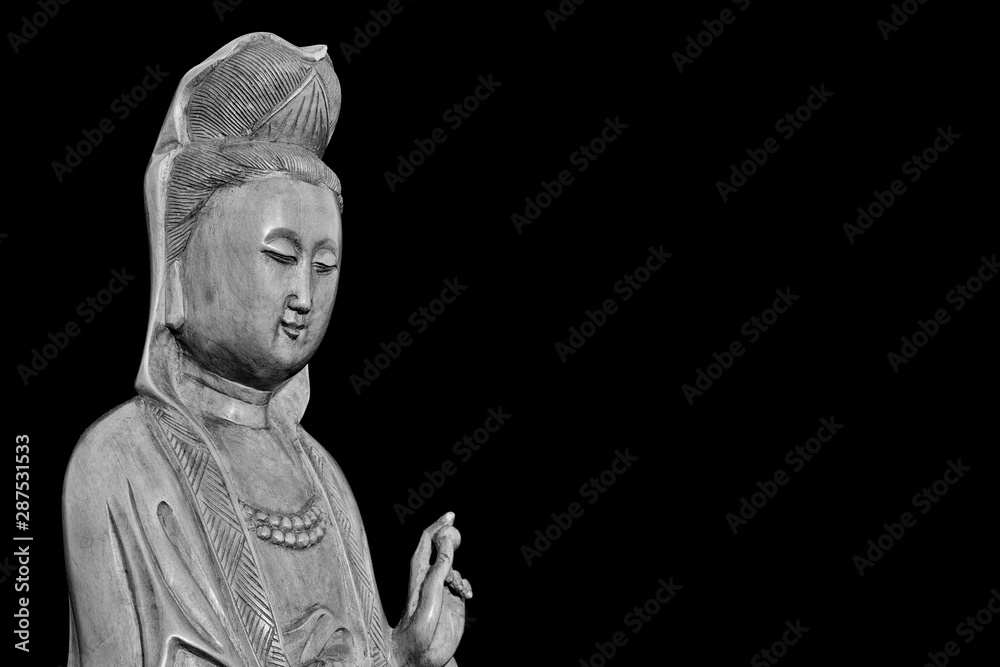 Buddhist religion and meditation. Kannon or Guanyin, the Goddess of Mercy, wooden statuette (Black adn White with copy space)
