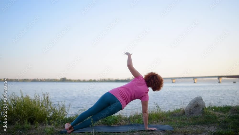 Girl with red hair relaxing while meditating and doing yoga exercise in the beautiful nature beside river Girl with red hair relaxing while meditating and doing yoga exercise in the beautiful nature beside river
