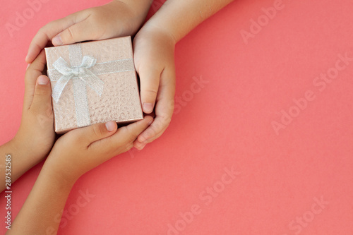 Baby hands hold gift box on pink background © Марина Сухачёва