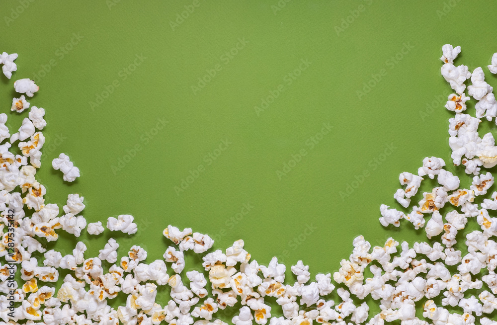 White tasty popcorn on a green background. Popcorn pattern on green background. Top view. Copyspace for your text.