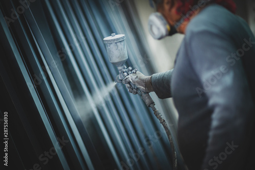 Man painting metal products with a spray gun photo