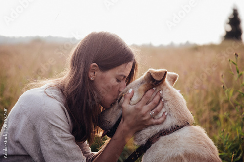 Human and a dog. Girl and her friend dog on the straw field background. Beautiful young woman relaxed and carefree enjoying a summer sunset with her lovely dog