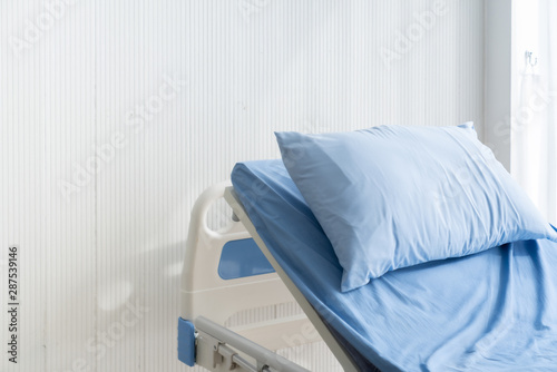 empty patient's bed scene with white wooden paint background in natural light scene / hospital and insurance concept / ward room photo