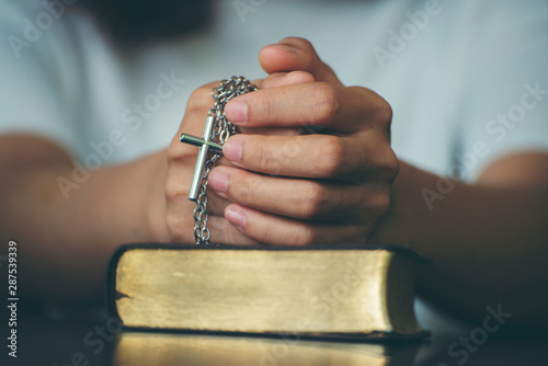 Pray and bible concept.Hand in hand together on bible by woman (worship christian), thinking and closed her eye at bed room. Person front view, Asian female praying, hope for peace, horizontal banner.