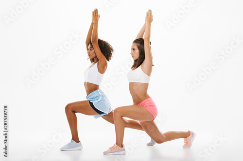 Portrait of two athletic multinational women in sportswear doing fitness exercise