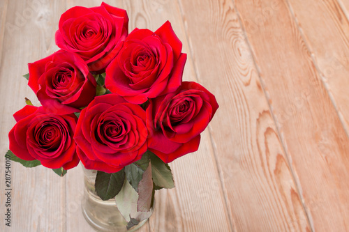 Red roses bouquet on wooden background with copy space. photo