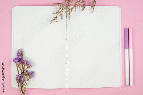 Top view of notebook stationery and flower on pink background