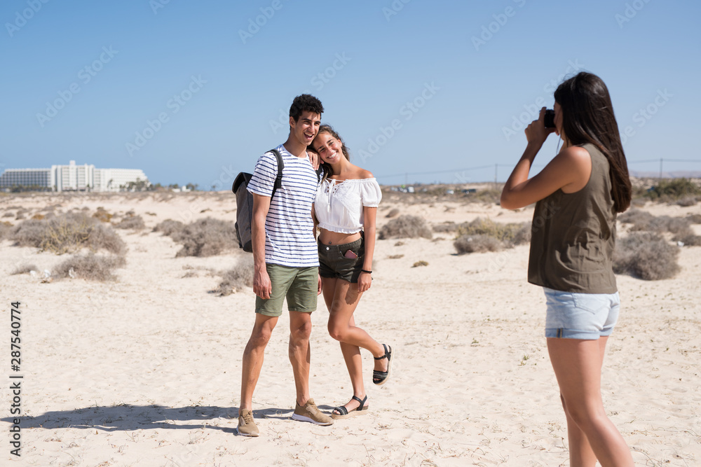 Woman taking a photo of a couple on a beach Woman taking a photo of a couple on a beach