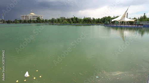 Dushanbe Flagpole Park Lake View of Swimming Duck with Ducklings and Palace of Nations at Background on a Cloudy Rainy Day photo