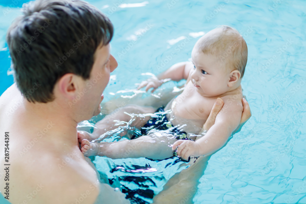 Happy middle-aged father swimming with cute adorable baby in swimming pool. Happy middle-aged father swimming with cute adorable baby in swimming pool.