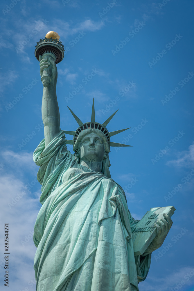 Fototapeta premium Shot of the Statue of Liberty in New York City, Usa. The shot is taken during a beautiful sunny day with a blue sky and white clouds in the background 
