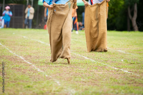 People running sack race in field in culture of countryside 