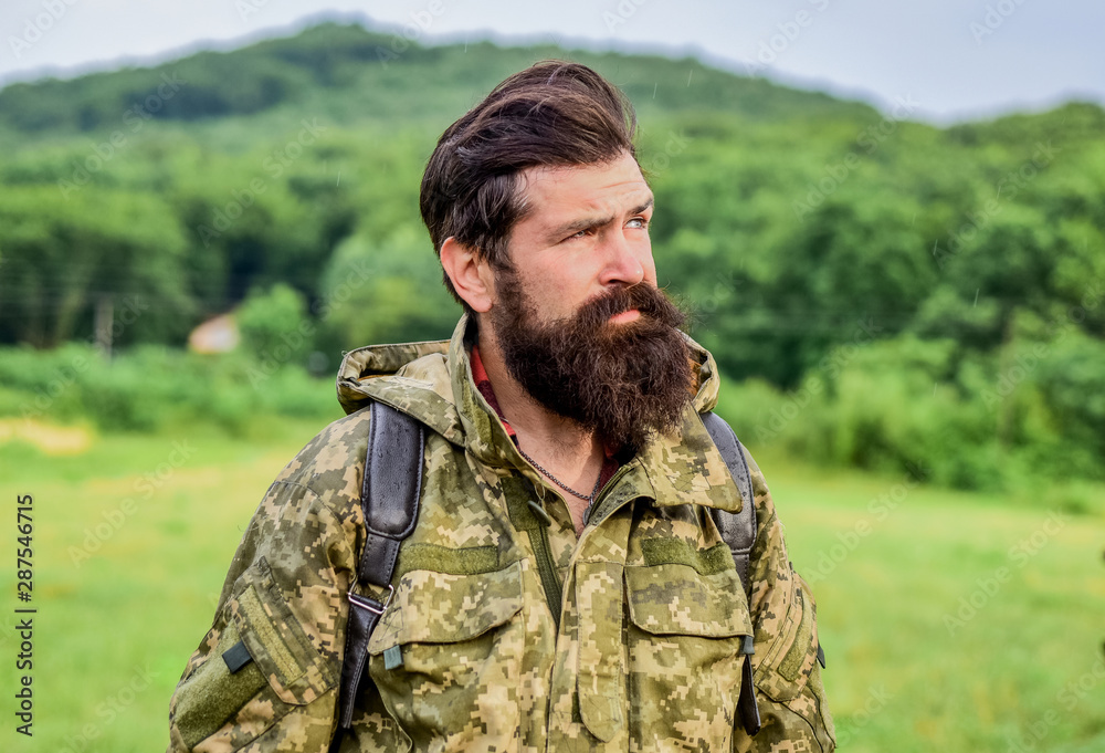 Brutal manly guy. Hike and travel. Weekend leisure and vacation. Hiker bearded man hiking. Hiker ready for adventures. Man bearded backpacker wear camouflage jacket nature background. Hiker tourist