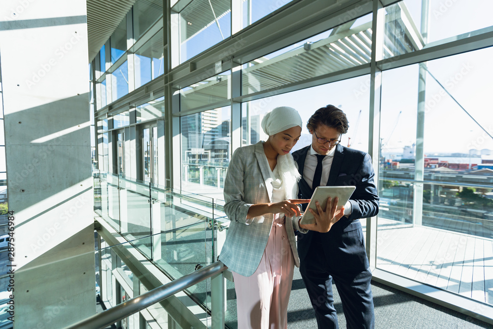 Business people working together on digital tablet in corridor at modern office