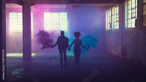 Couple running with distress flares in industrial building photo