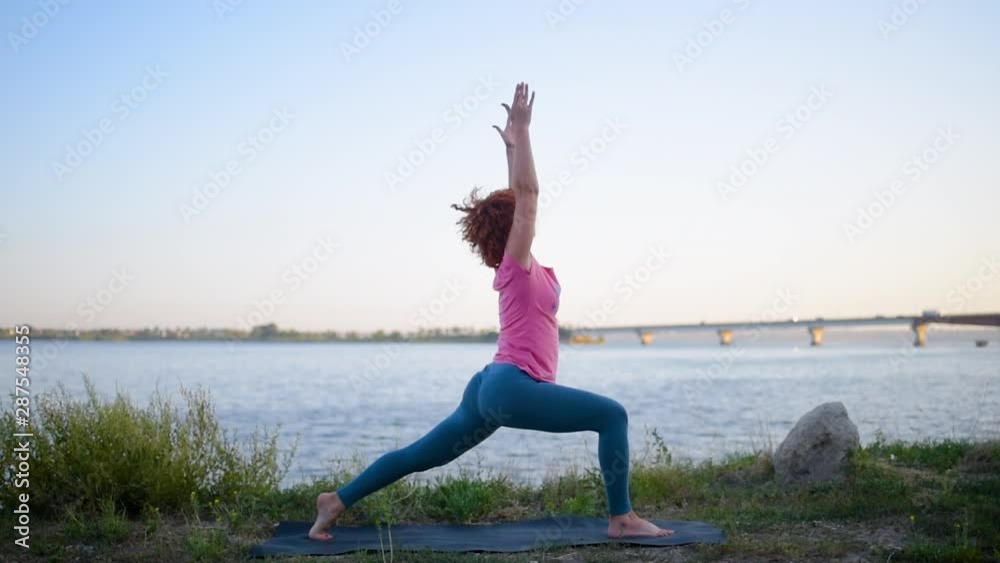 Girl with red hair relaxing while meditating and doing yoga exercise in the beautiful nature beside river Girl with red hair relaxing while meditating and doing yoga exercise in the beautiful nature beside river