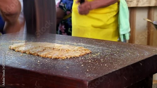 Close-up Thai chef is using a wooden hammer to thai desert peanut sesame snack (Candy Toob-tub) on wooden table to a homogeneous. Candy Toob-tub is a dessert with nuts and sugar.